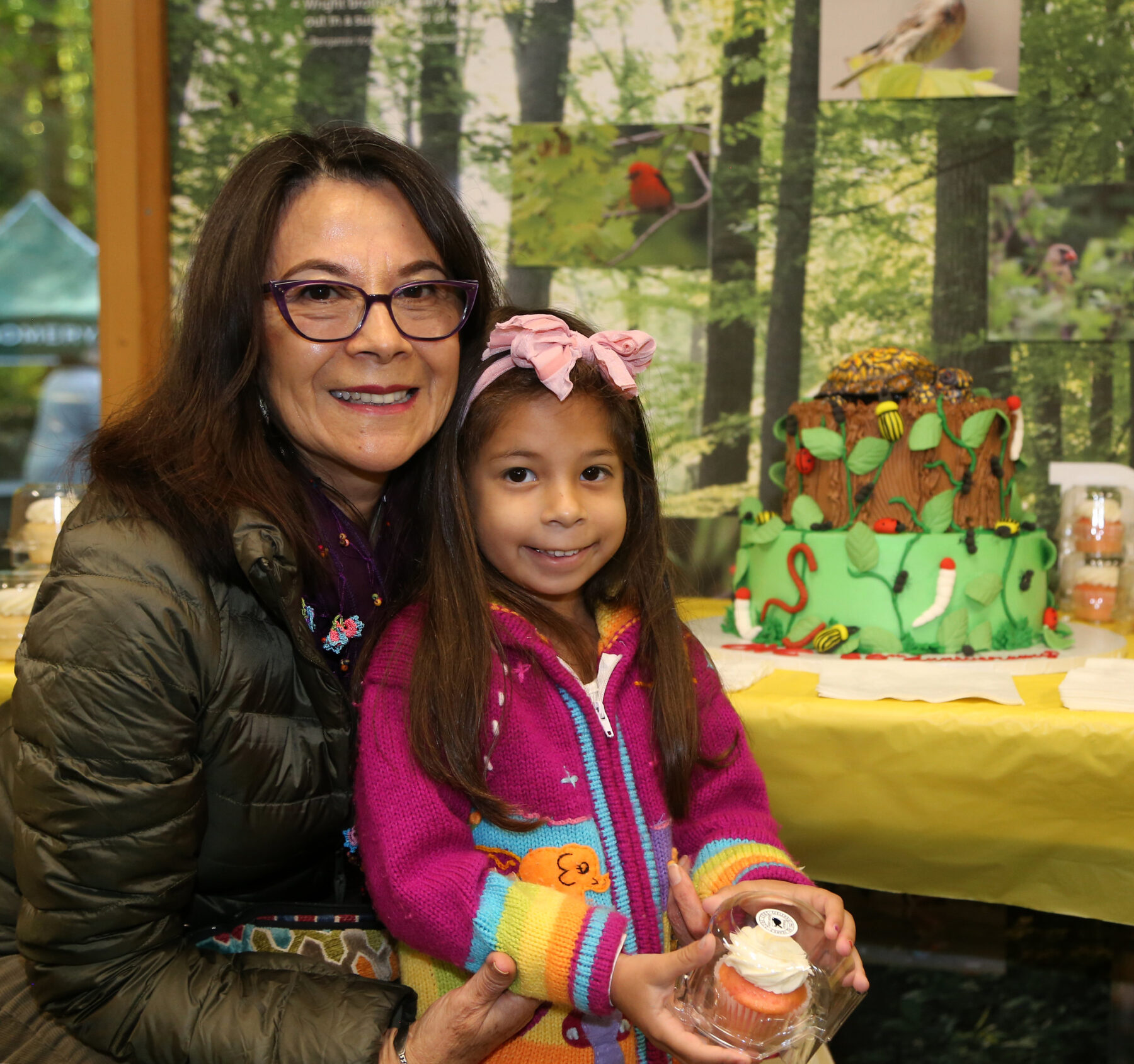 An adult and child stand next to a colorful cake
