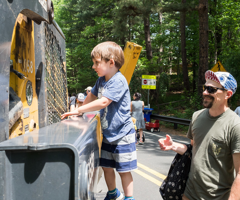 Child climbs Parks truck while parent smiles and watches