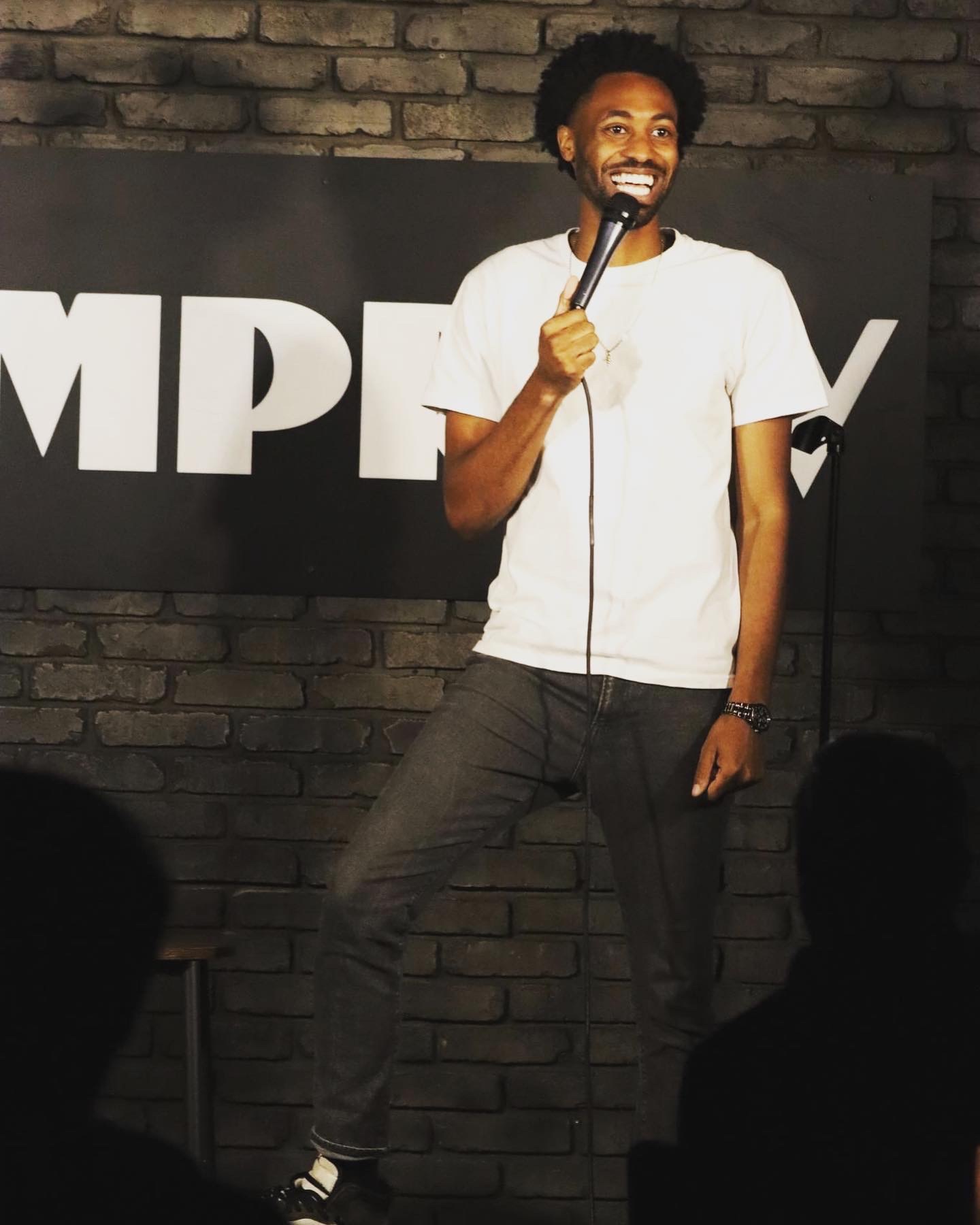 Comedian Benjamin Nwokeabia smiles on stage with a mic