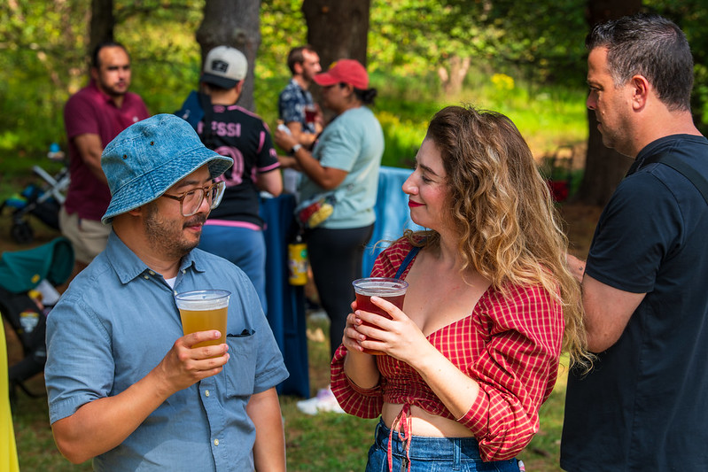 Couple holding beers, looking at each other.