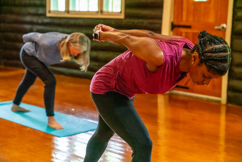 Women beding over at waist with arms clasped behind their backs.