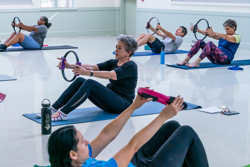 People doing mat pilates holding rings.