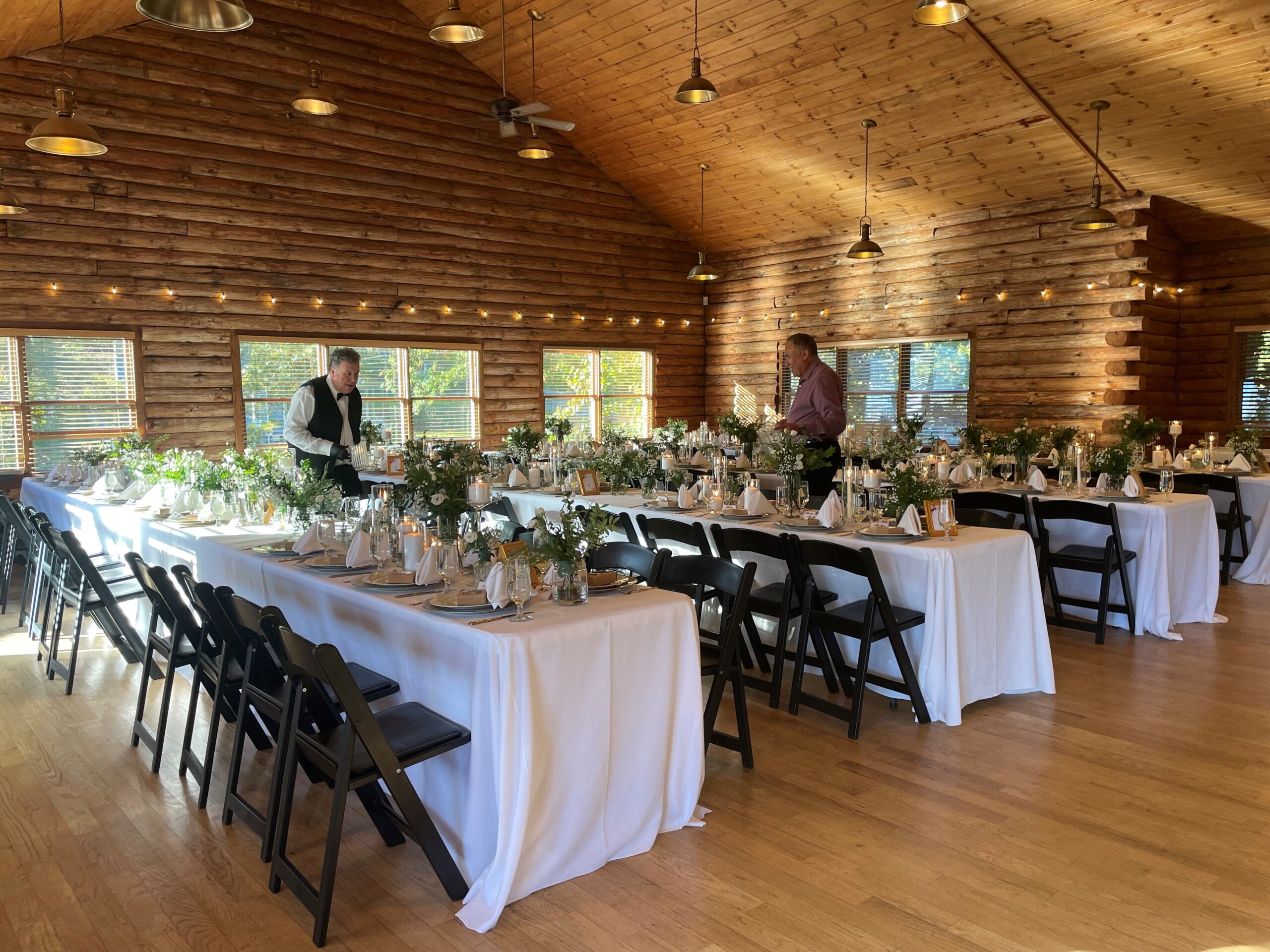 Interior or a rustic lodge is set up with formal tables for a special occassion.