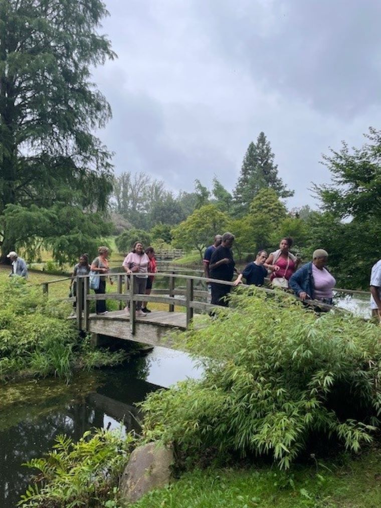 A group of Trail Trekkers walk across a bridge over a stream.