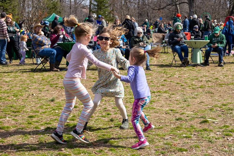 3 children hold hands and dance in a circle