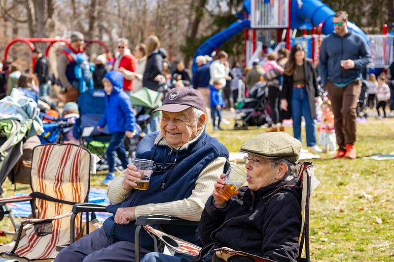 Older couple smiles in chairs while drinking beers