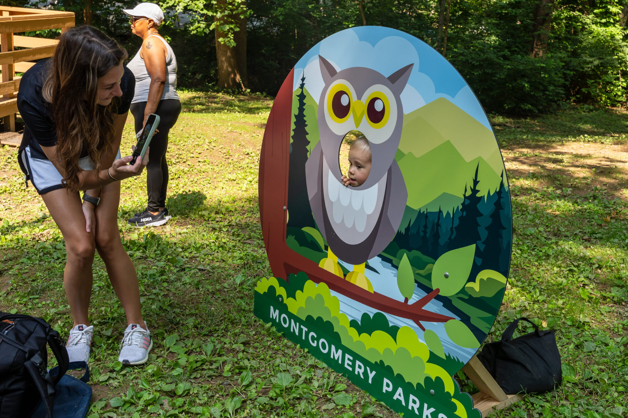 Child poses in owl face-in-the-hole picture stand while parent takes a photo