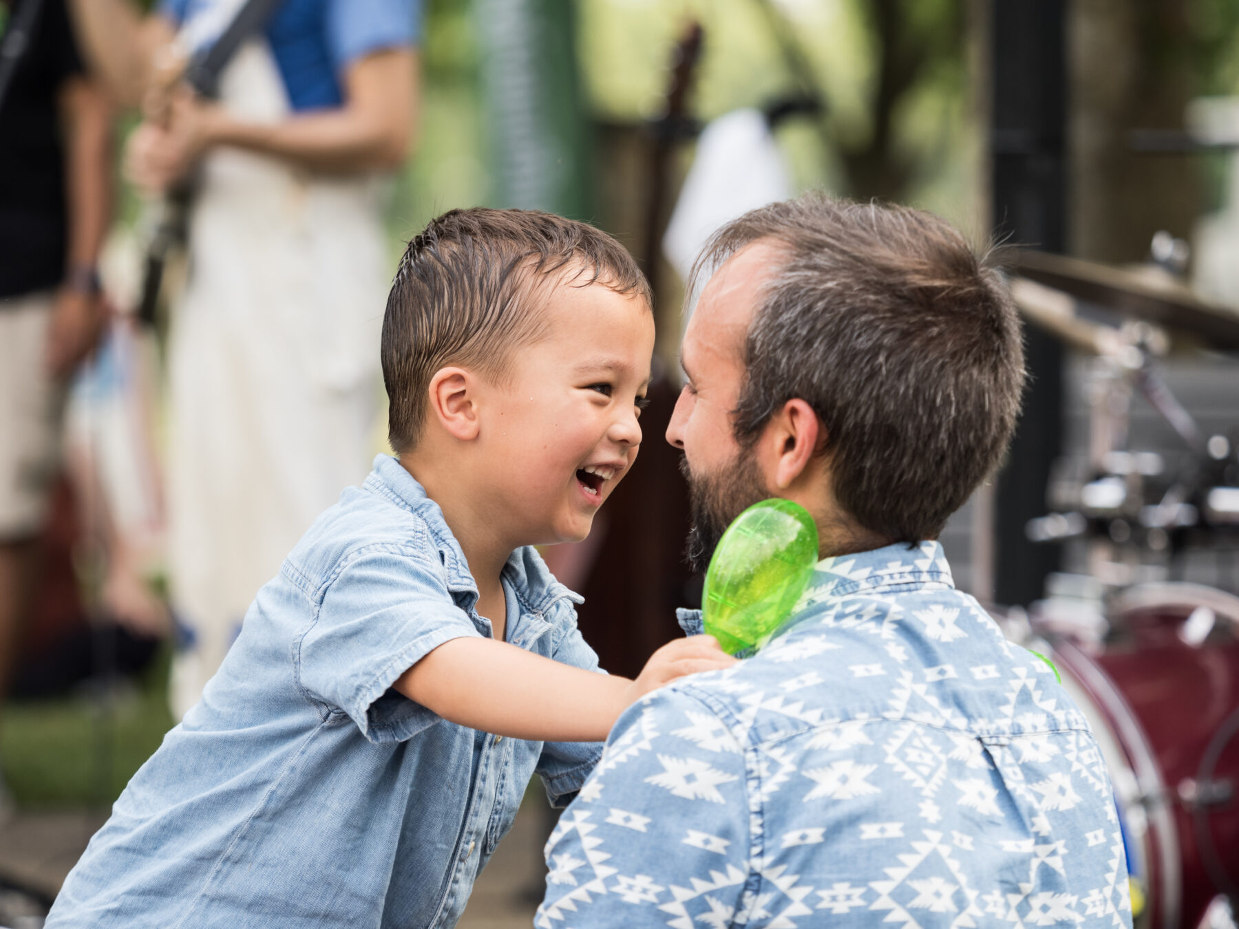 Child smiles at parent while holding maraca
