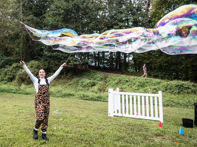 Bubble performer holds up a long bubble at Parks Ale Trail
