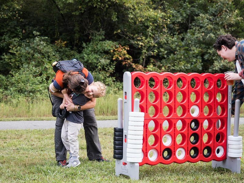 Parent hugs child while playing jumbo connect four at Parks Ale Trail