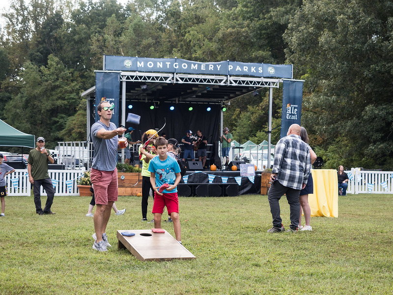 Attendees play cornhole with main stage in the background at Parks Ale Trail