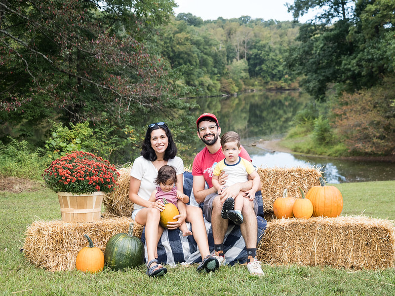 Family poses and smiles for camera on hay and pumpkin setup