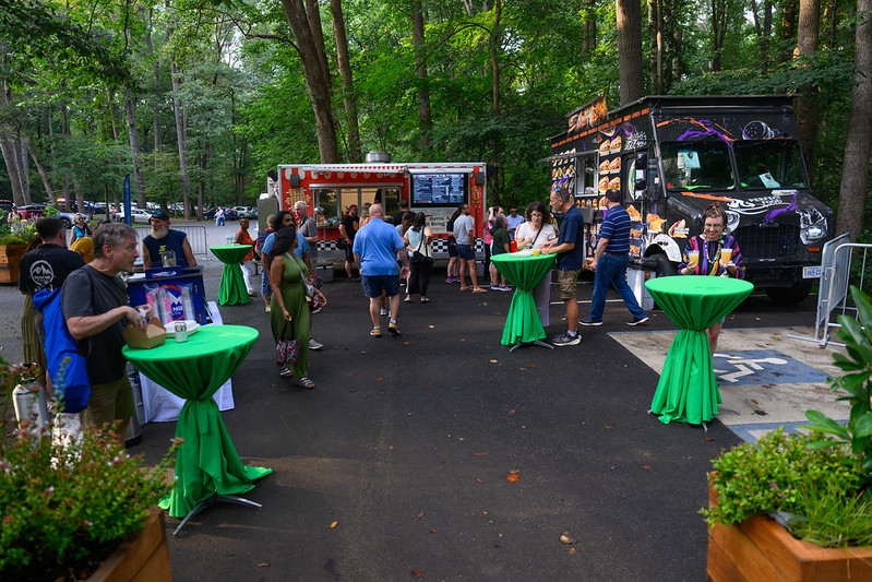 2 food trucks and tables sit out with attendees hanging out