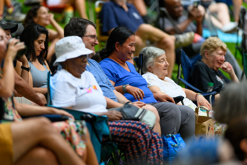 Audience members laughing while sitting in lawn chairs