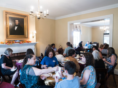 A group of people seated at round tables inside Woodlawn Manor enjoying a high tea.
