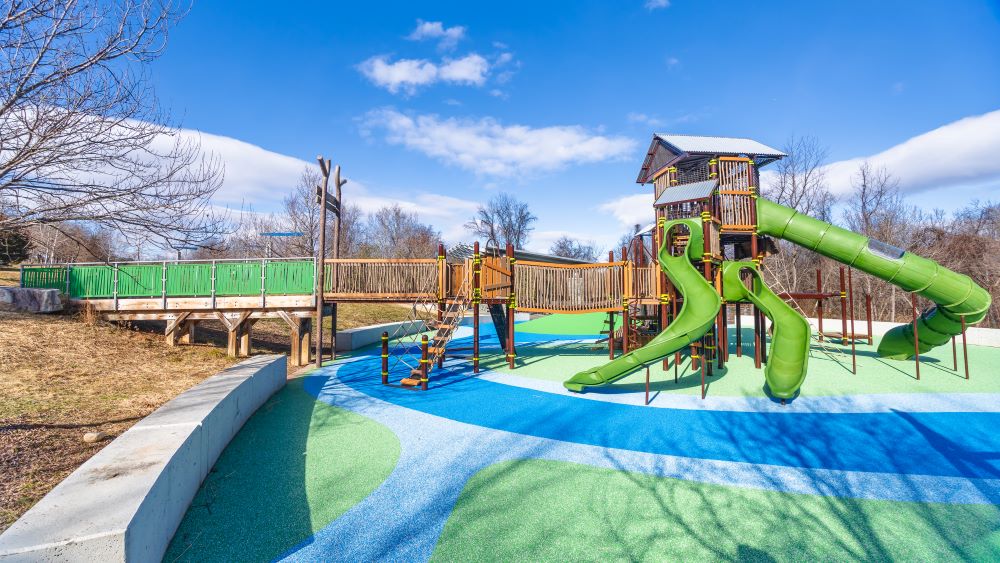 Side angle of the large playground at Greenbriar Park with 3 slides