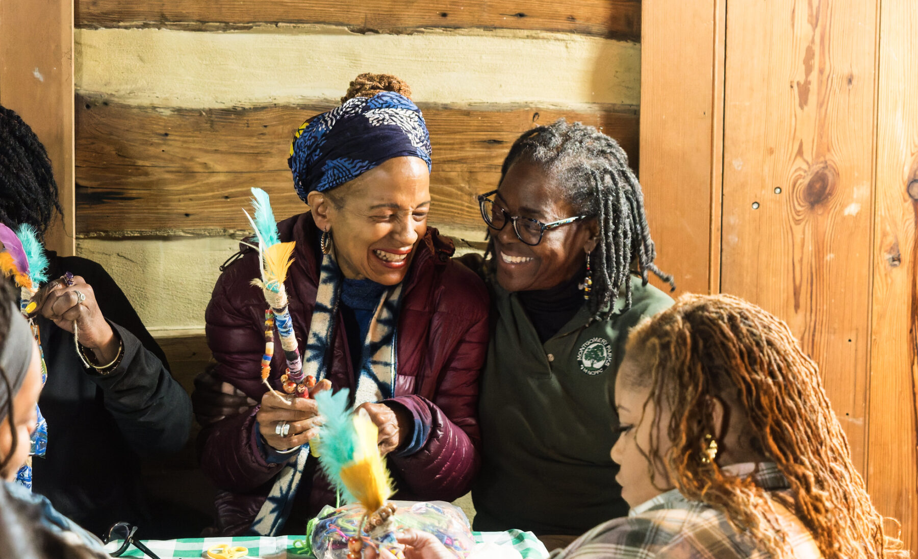 Two people smiling while working on a craft at Oakley Cabin