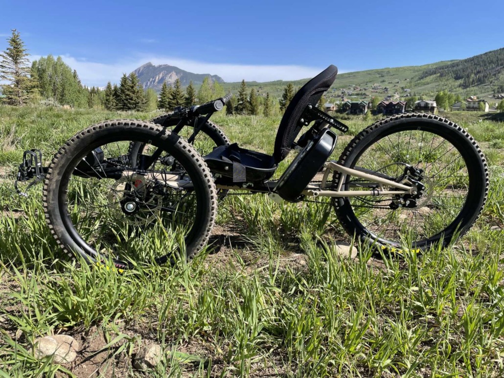 three-wheeled foot-pedaled recumbent bike sitting in an open grass field