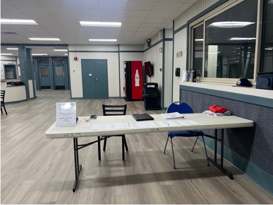 A picture of a foldable table that sits next to a large window on the right with doors and a vending machine in the background
