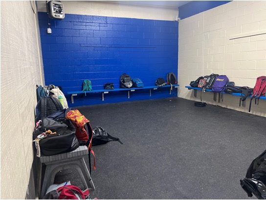 Small room with benches on the three walls and backpacks on the benches. The middle back wall is painted blue