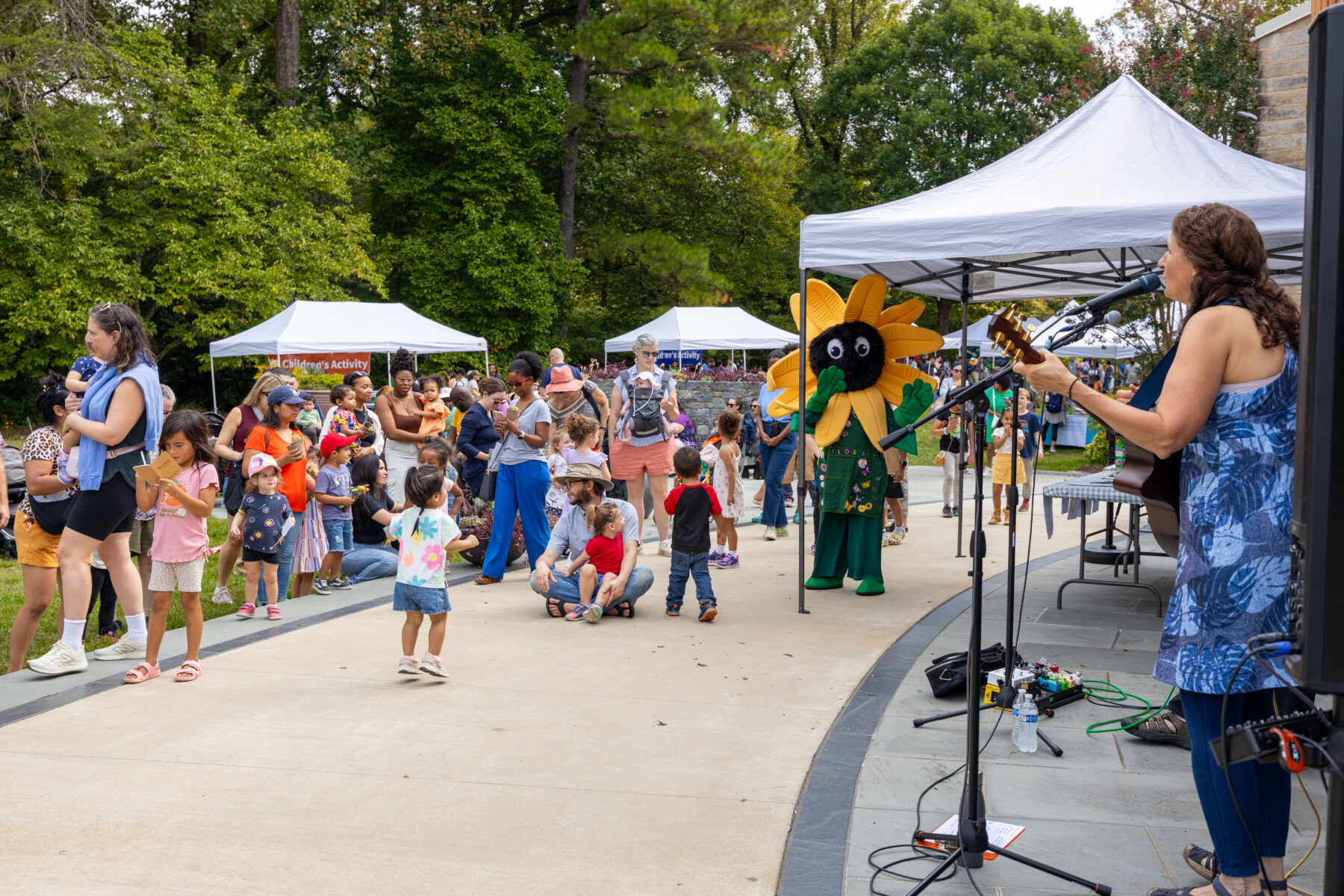 Woman singing and playing guitar to young audience at children's day in brookside gardens 