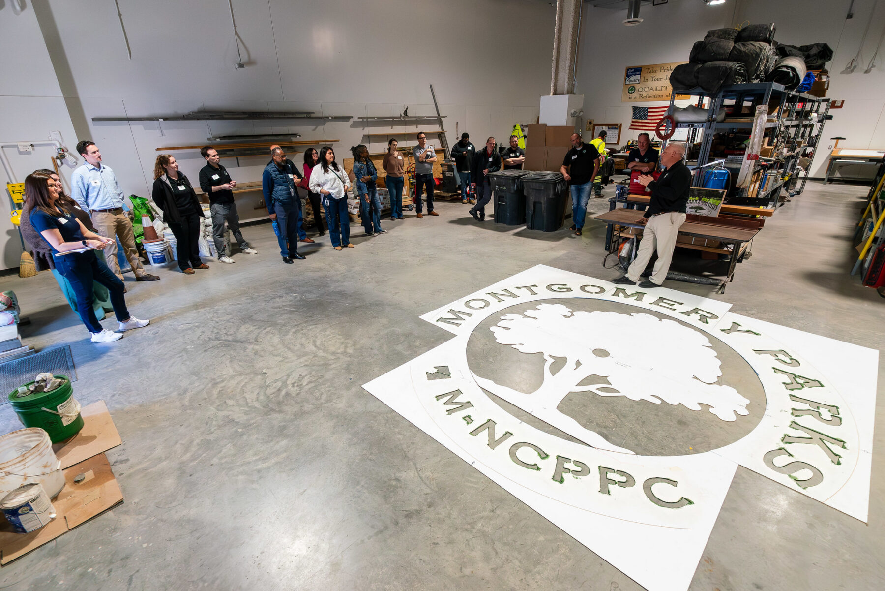 Montgomery Parks staff listening to a colleague, large logo stencil on the ground
