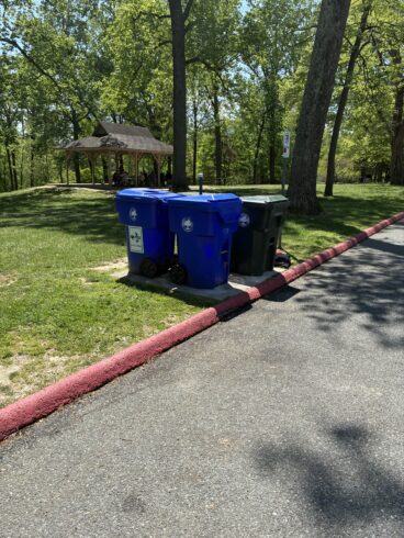 recycling and trash receptacles in a park. 