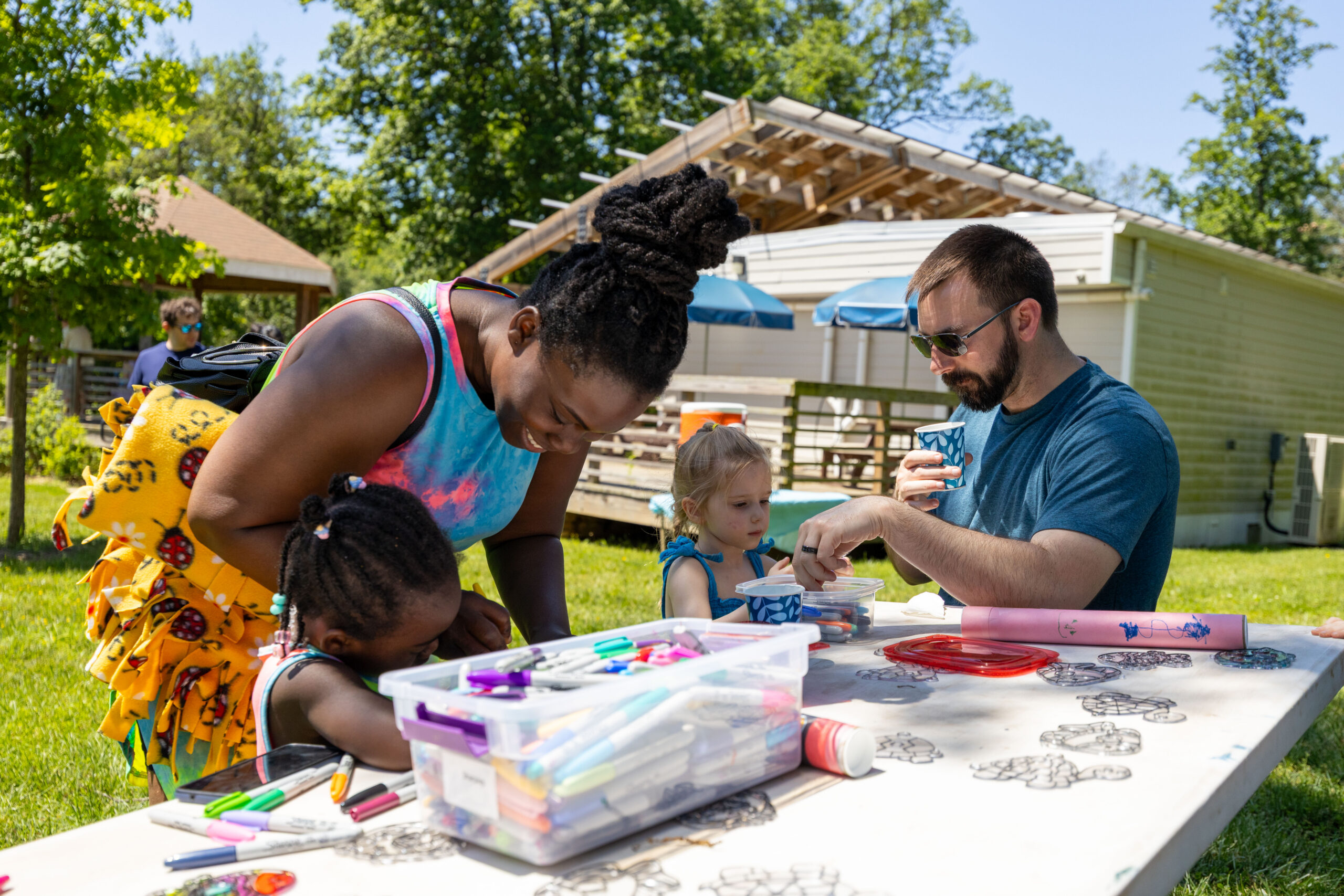 Adults and children outside at a table coloring.