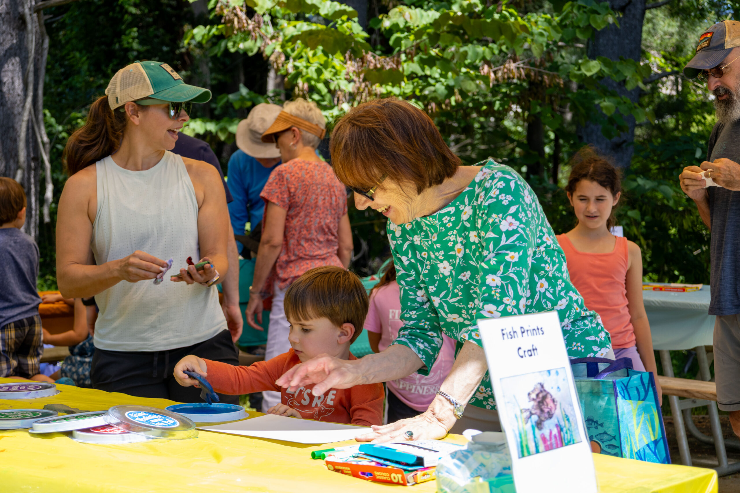 People standing around an activity table wearing sunglasses and hats.