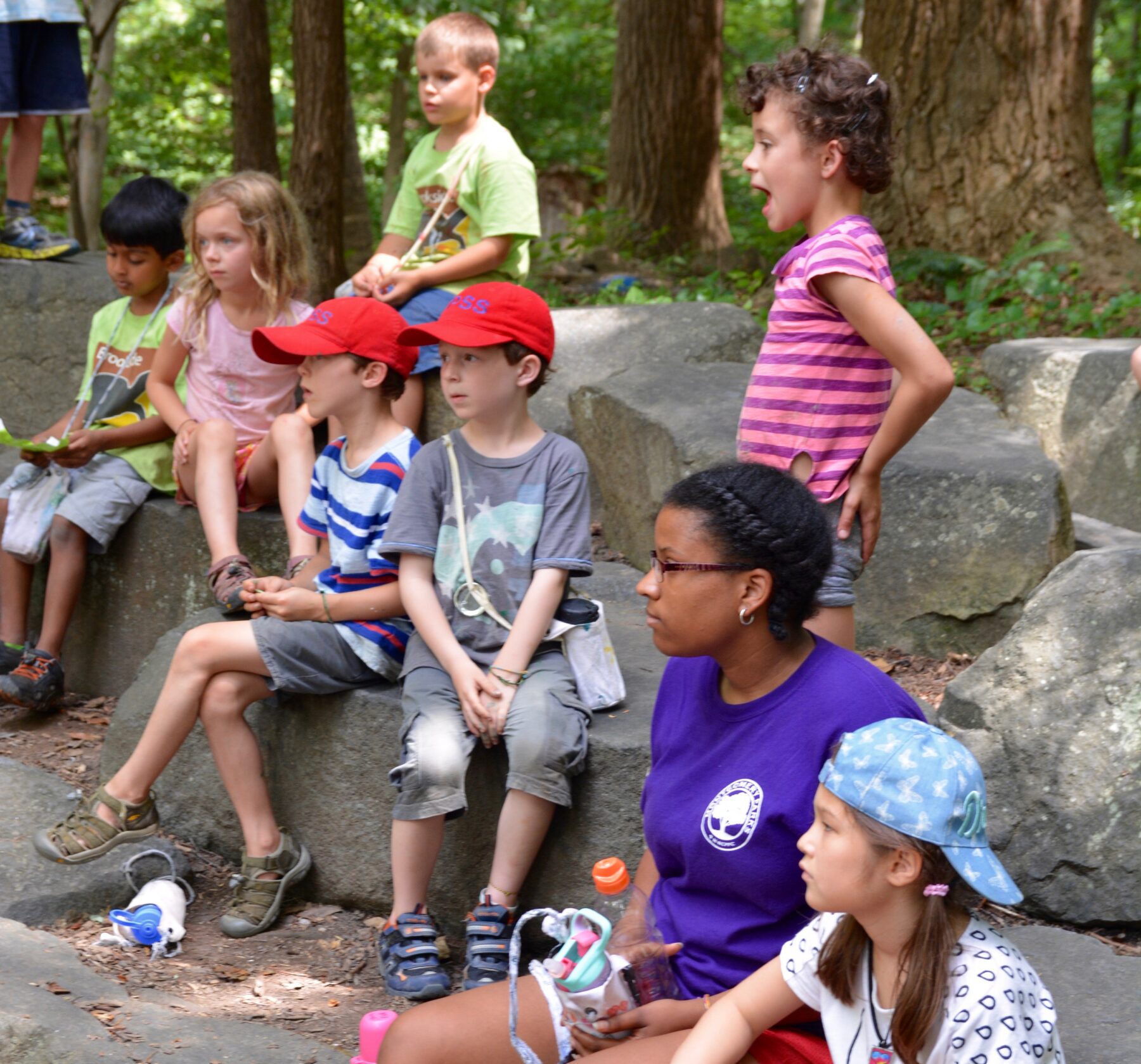 Kids and camp counselors sitting on large rocks