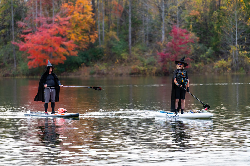 Two attendees dress up in witch costumes on paddle boards