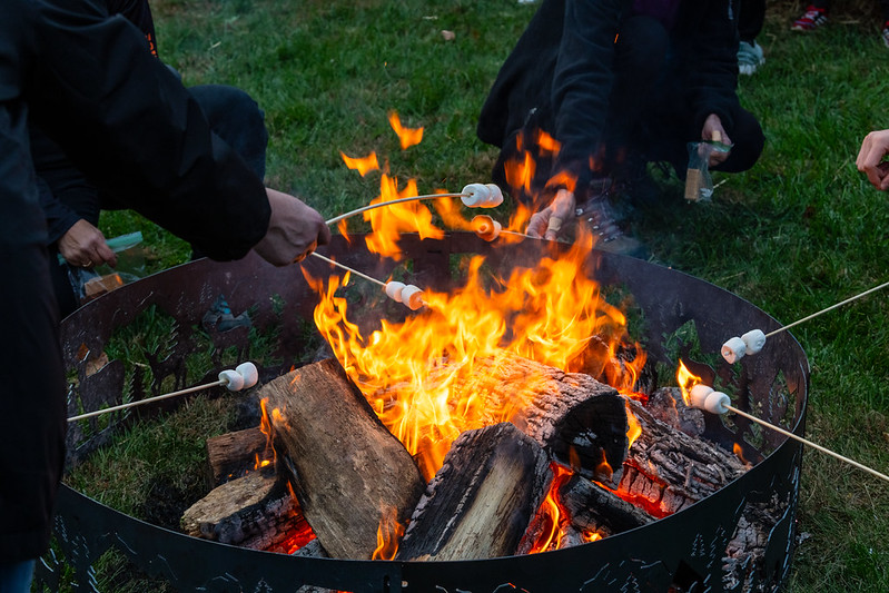 Attendees roast marshmallows over fire pit