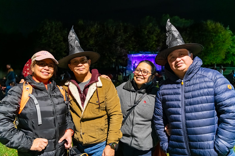 Attendees smile for camera, two are wearing witch hats