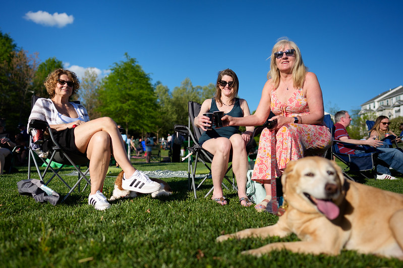 Attendees smile at camera holding beer with tan dog sitting besides them
