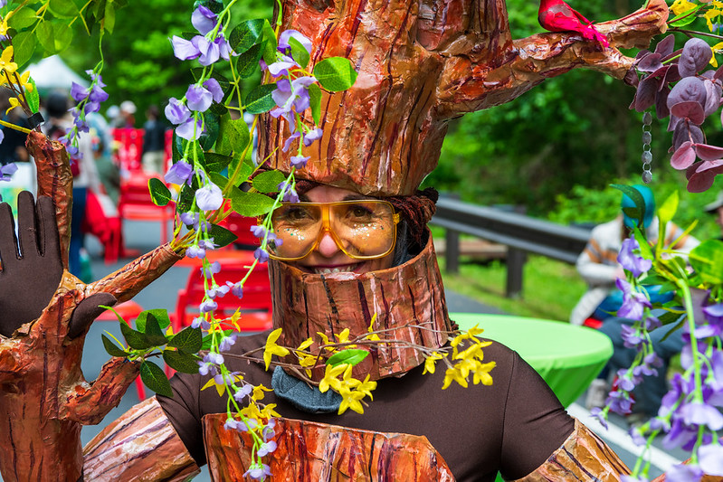 Vendor dressed in tree costume with flowers smiles at camera