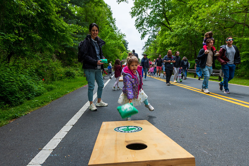 Attendee and child play cornhole