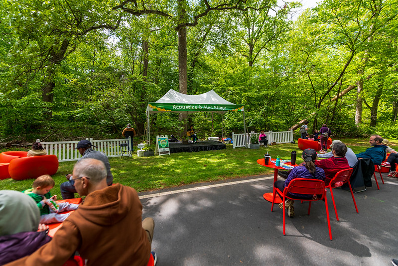 Acoustics and Ales stage with attendees watching performer play acoustic guitar