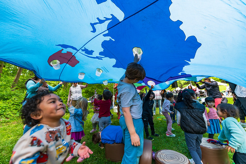 Kids play under blue parachute