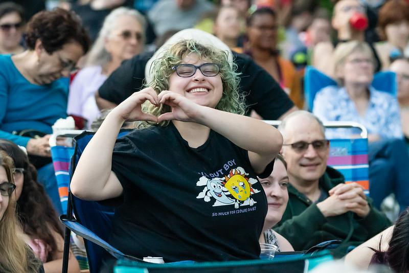 Attendee makes a heart with two hands smiling at camera