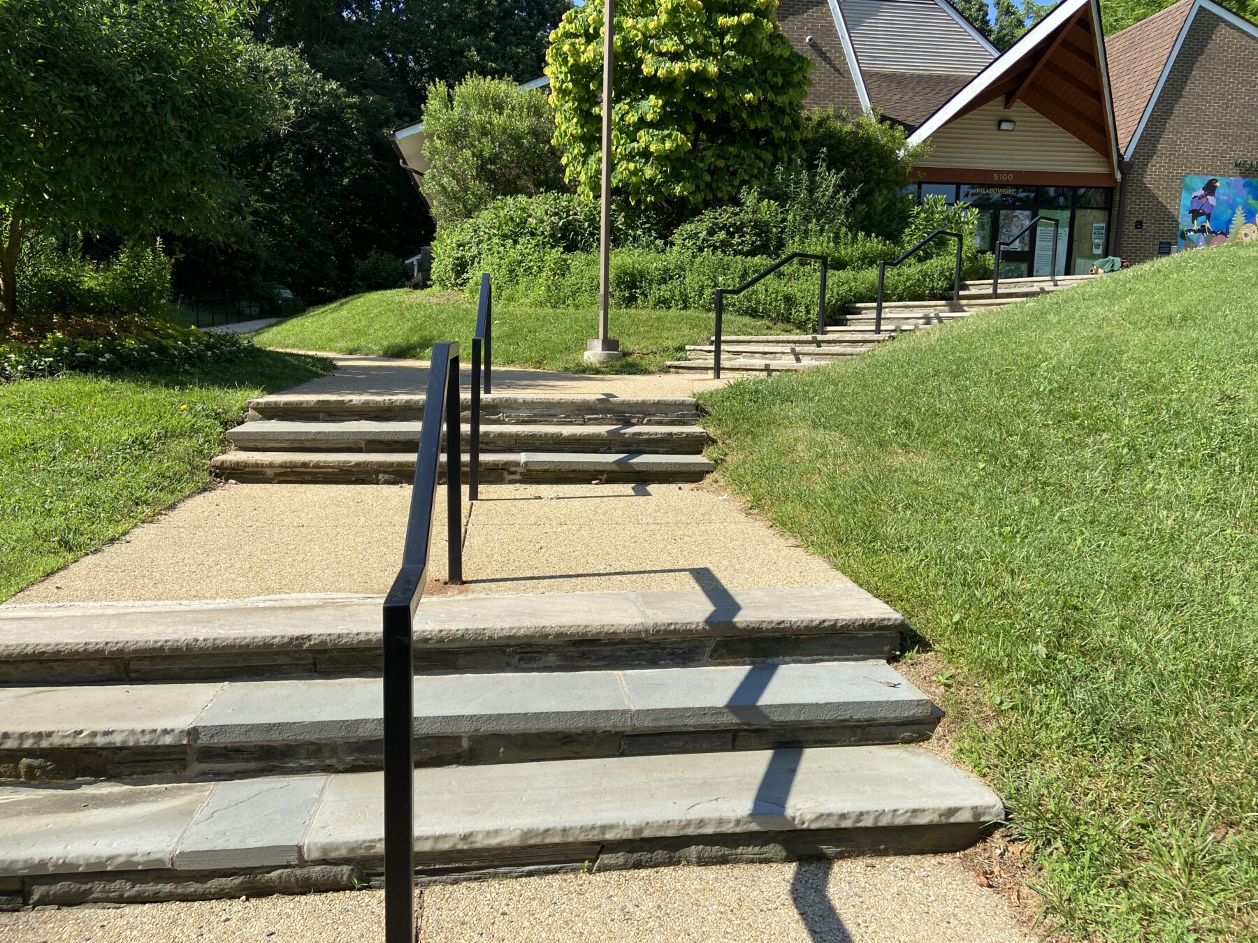 Front steps to meadowside nature center with black railing in the middle