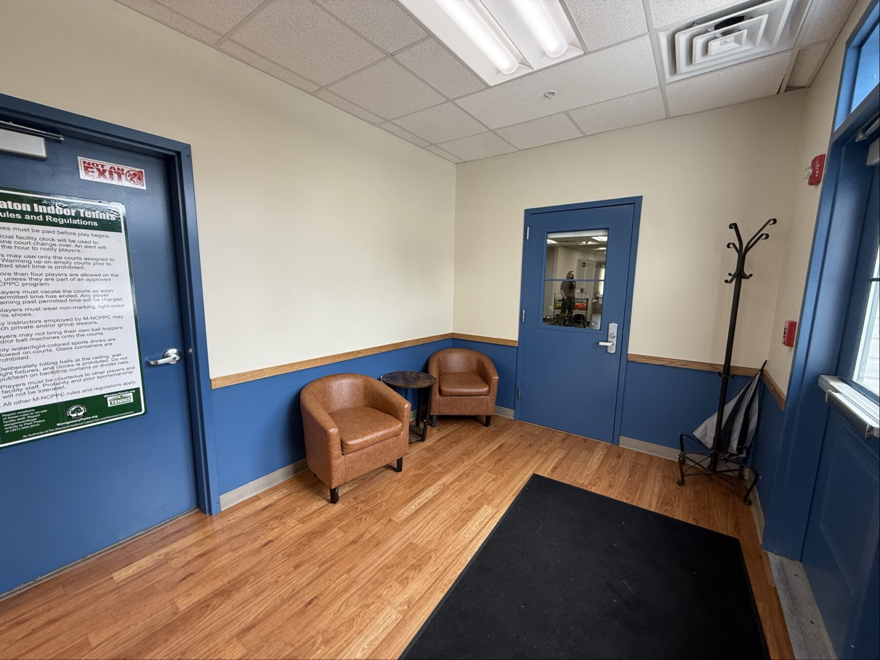 Two brown chairs in the left corner with a door on the right side of the chairs and another door to the left of them