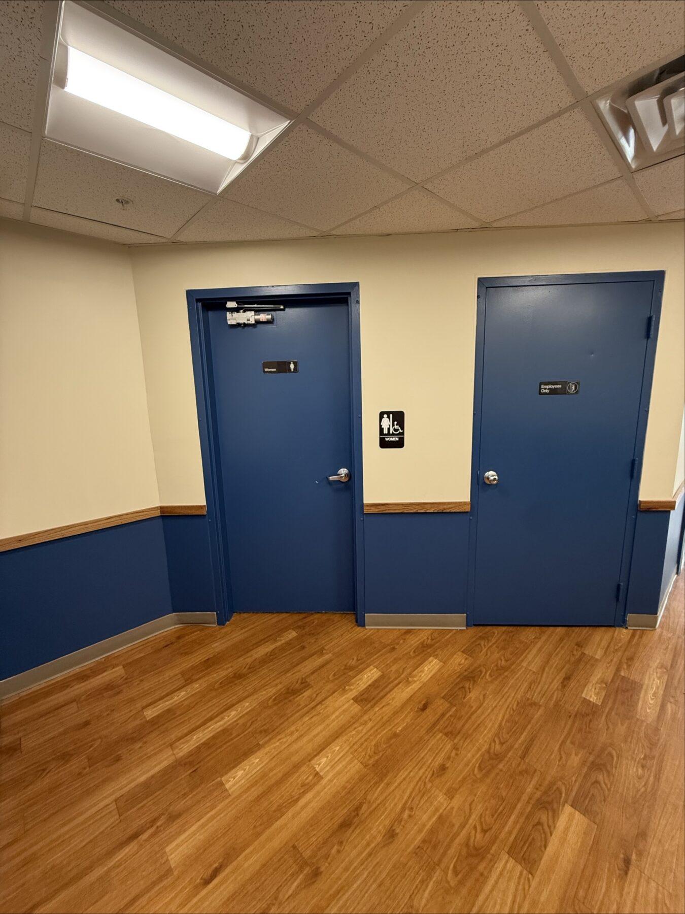 Picture displays 2 doors . One on the left that leads to the women's rest room with a black sign to the right of the door labeled women's and to the right of that is a second door with a "staff only" label on it