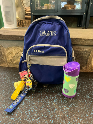blue monogramed bookbag with water bottle next to it