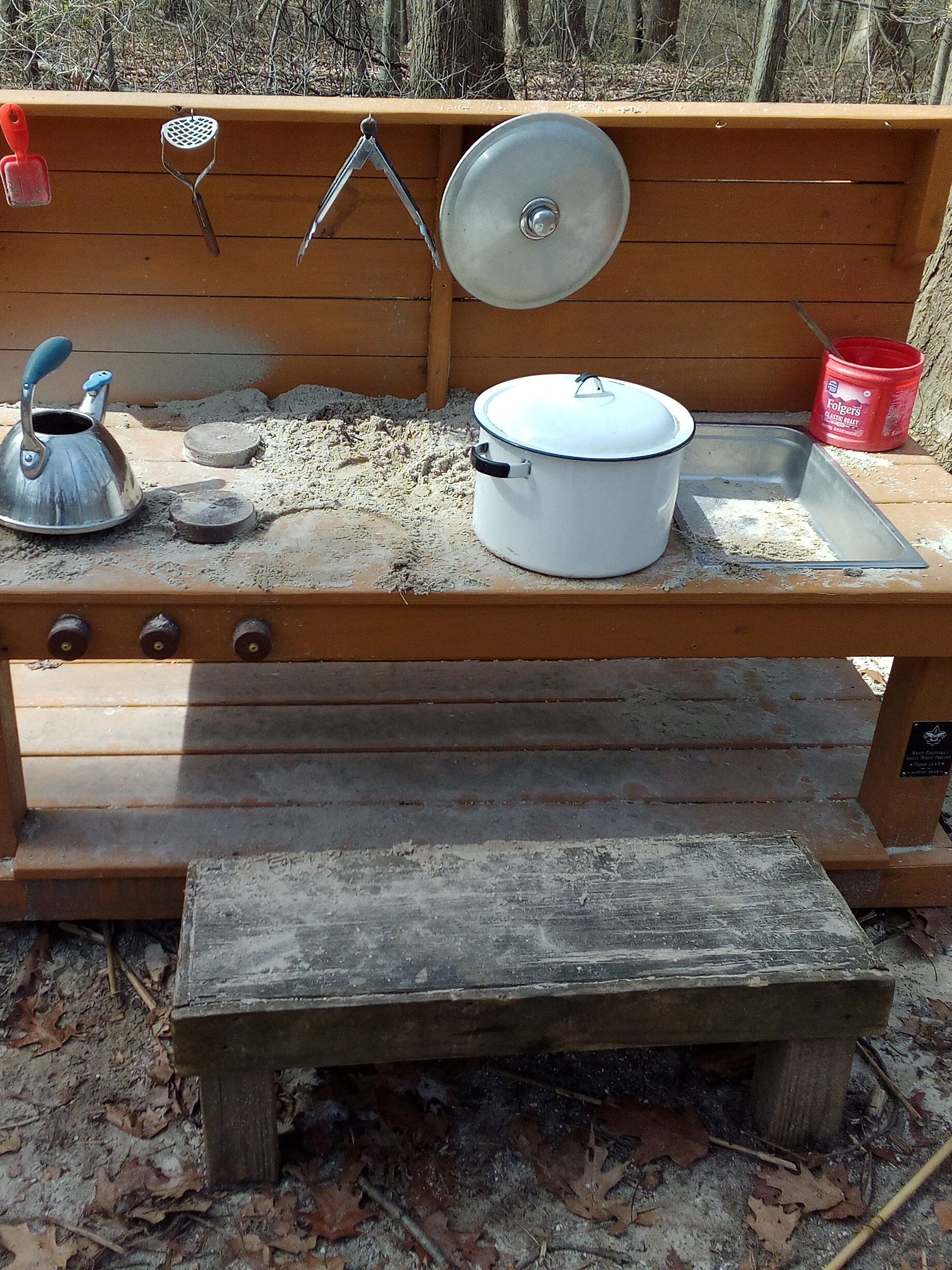 A small wooden table with plastic utensils and a small "sink" on the right