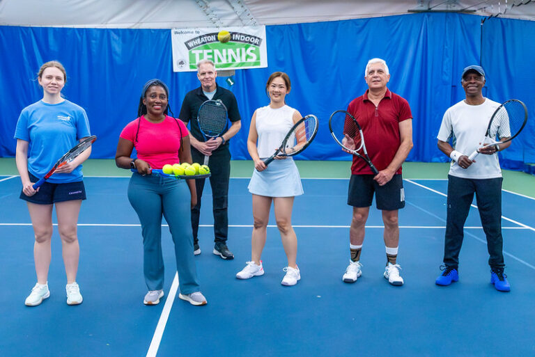 Adult tennis players with a coach on the coart