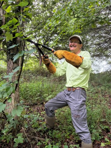 Volunteer Weed Warrior Supervisor cutting a vine with loppers