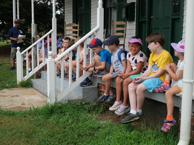Kids lined up sitting on a porch outside