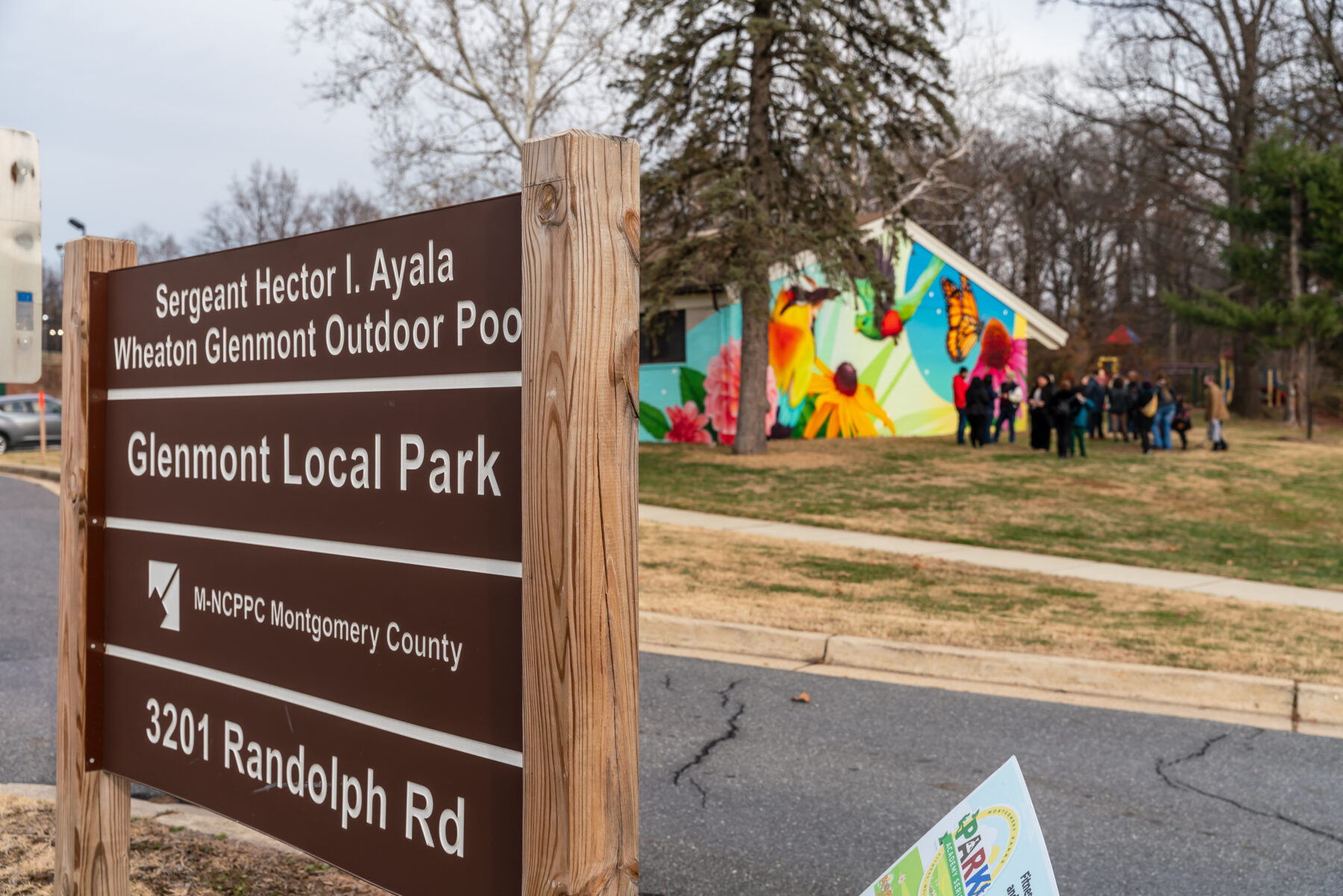 Glenmont Local Park sign with mural on the public activity building in the background.