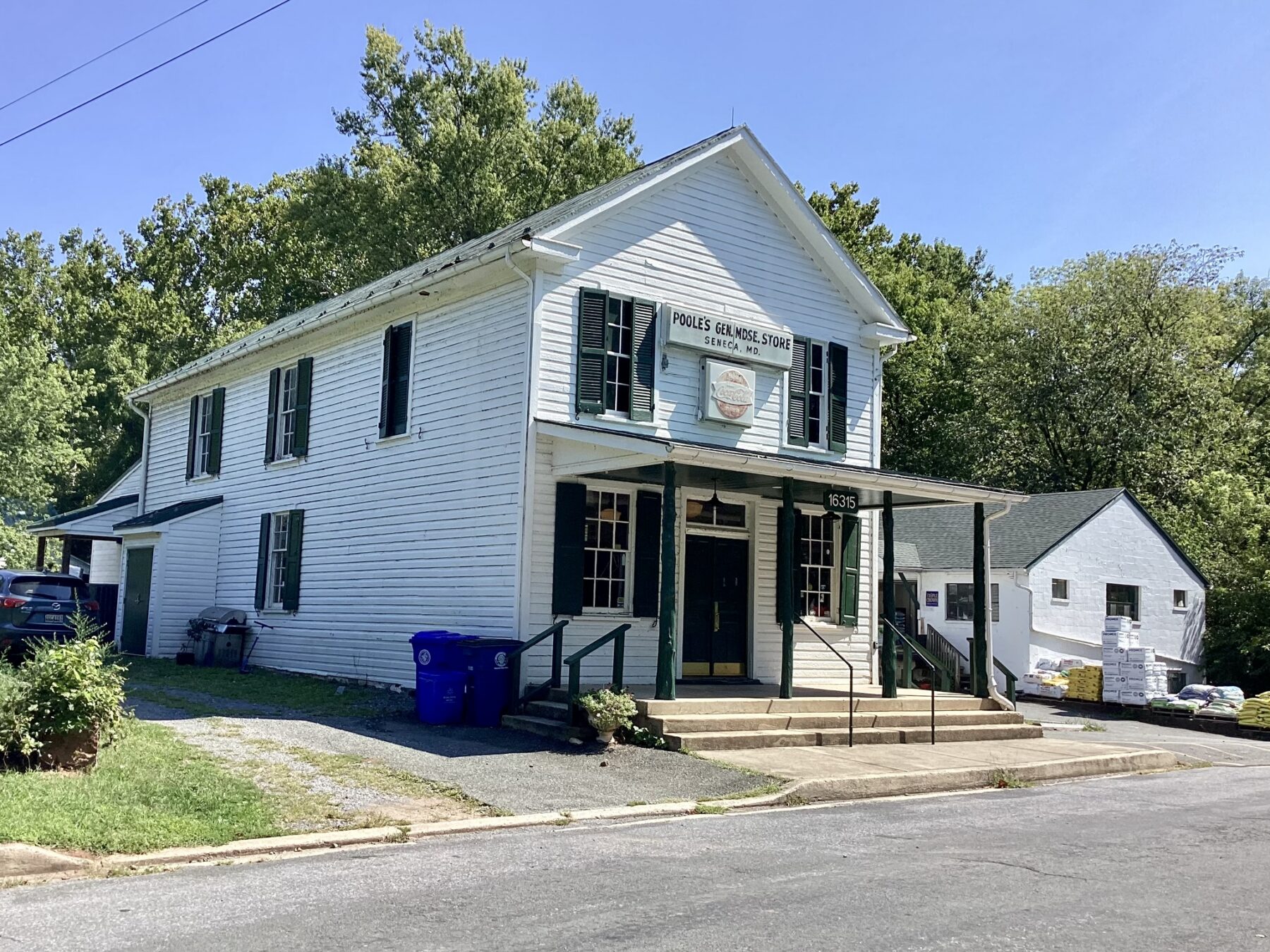 two story frame white house with front porch and asphalt parking area