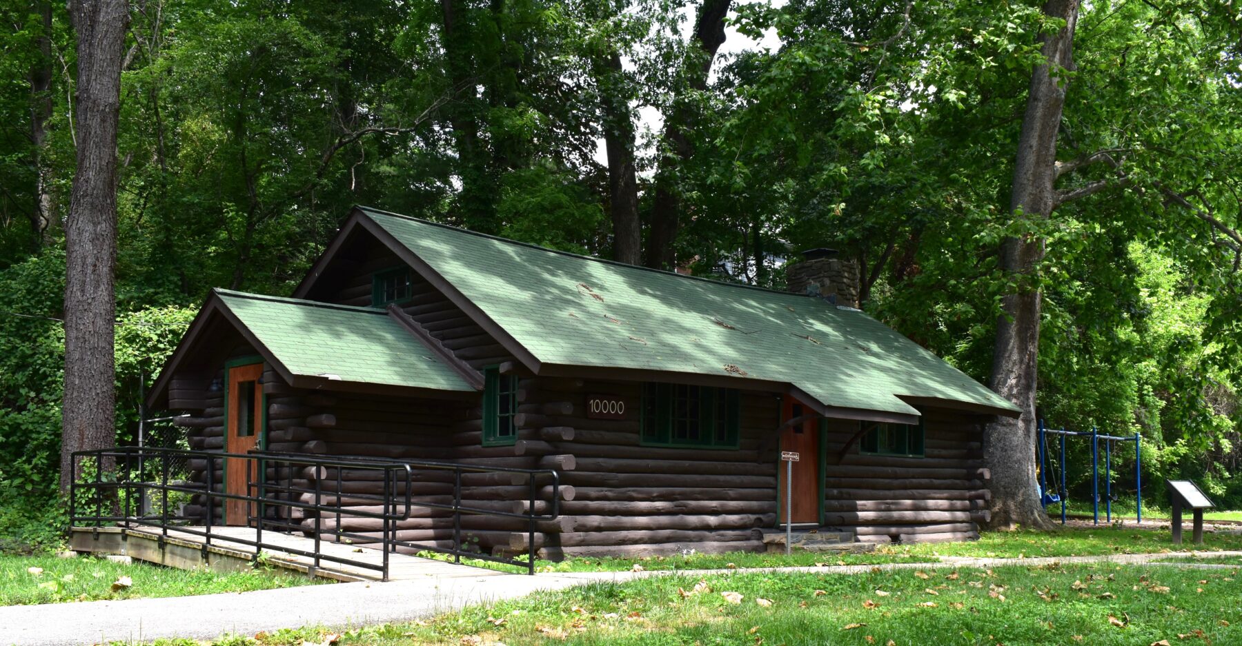 one story log cabin with green roof in the woods